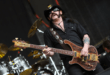 James Hetfield de Metallica, avec son visage expressif et sa guitare électrique, rendant hommage à Lemmy Kilmister de Motörhead, qui arbore son célèbre chapeau de cowboy et joue de la basse avec son énergie caractéristique sur scène.
